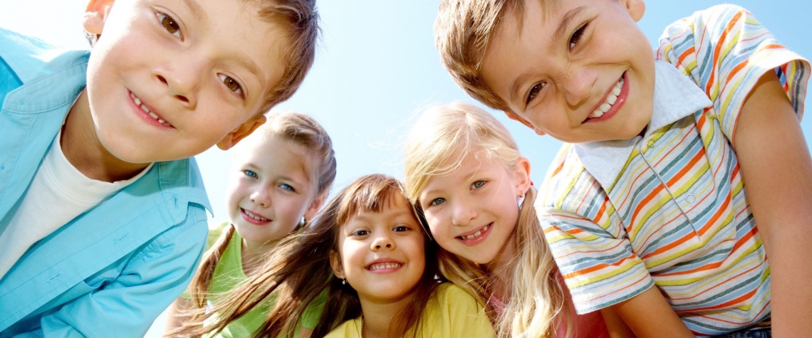 Five children look down at a camera and smile