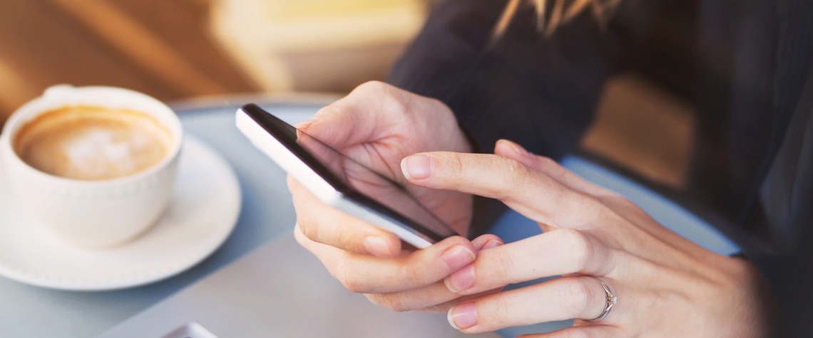 An ENB customer does her mobile banking on her phone over a latte