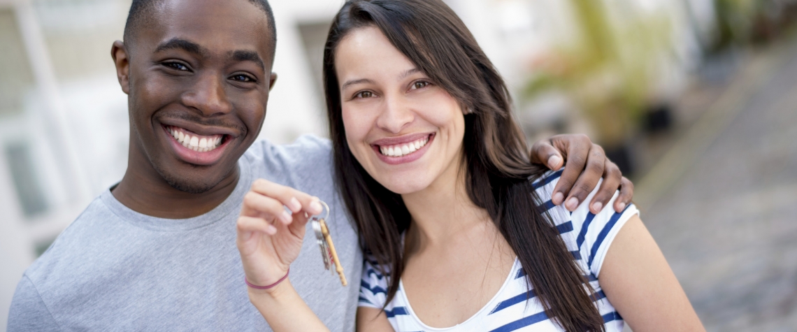 A young couple holding keys to their new home