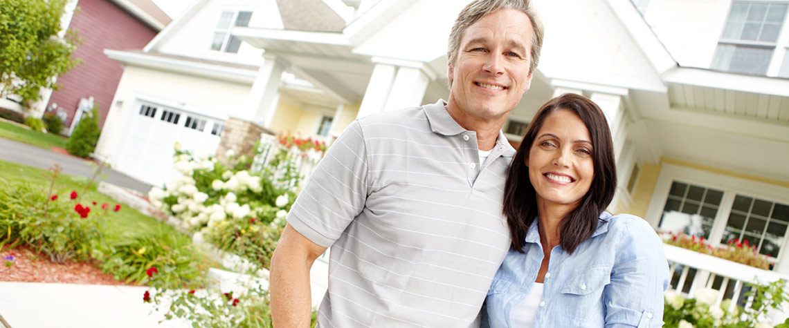 Two homebuyers stand outside their new house