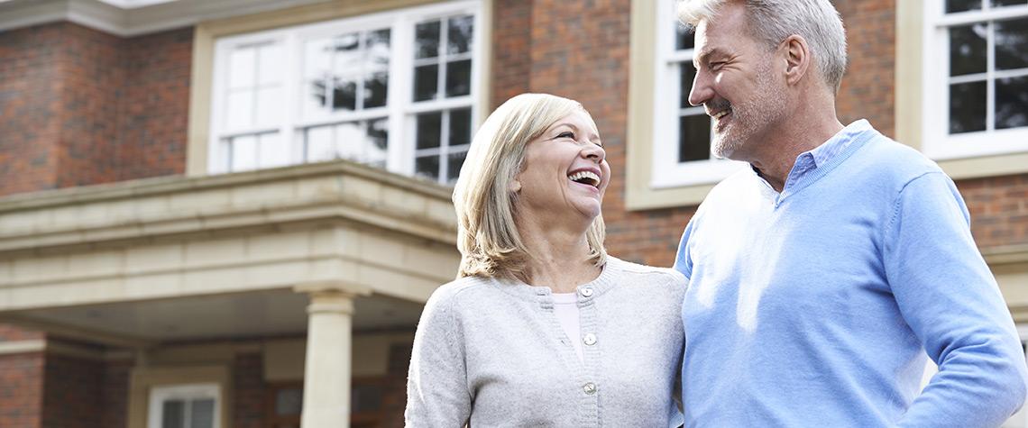 A man and woman laughing together in front of their home