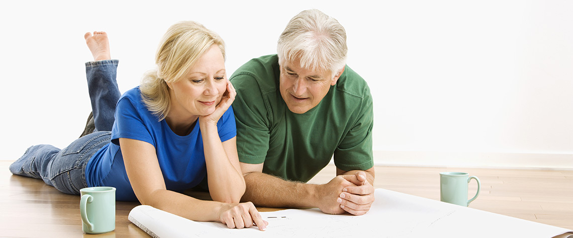 A male and female couple reviewing blueprints on the floor