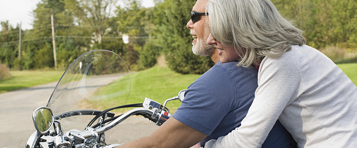 A man and woman riding a motorcycle outdoors