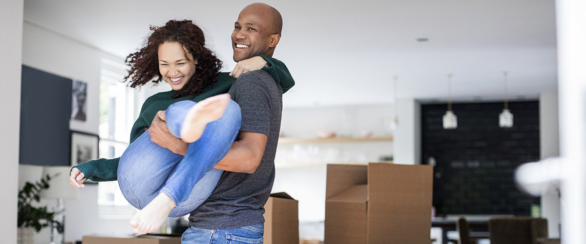 A man lifting a woman in a room with moving boxes