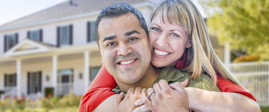 A male and female couple in front of a home