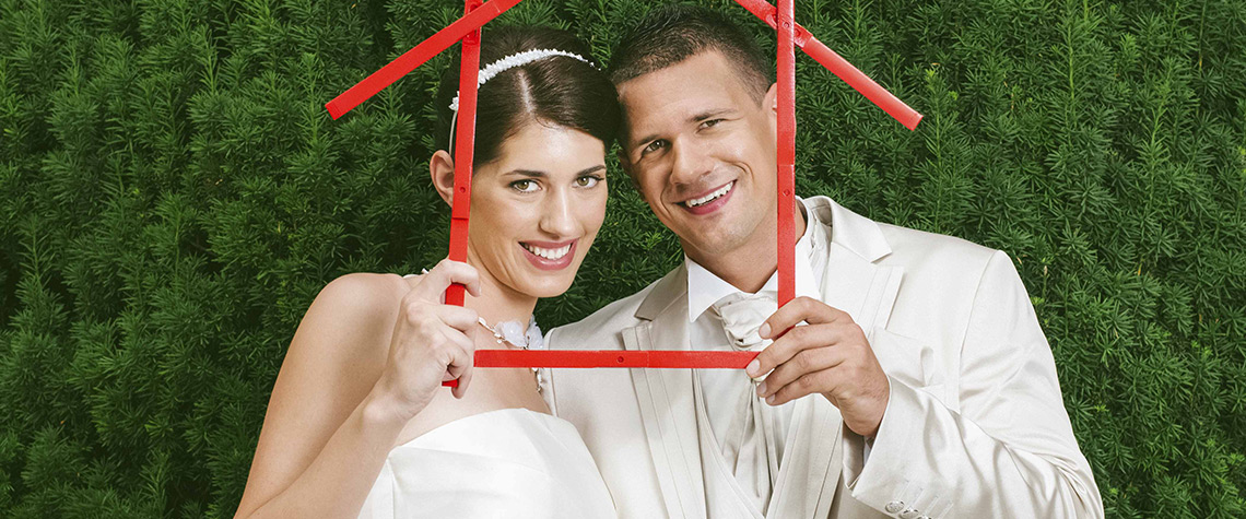 A newly married male and female couple holding the outline of a home