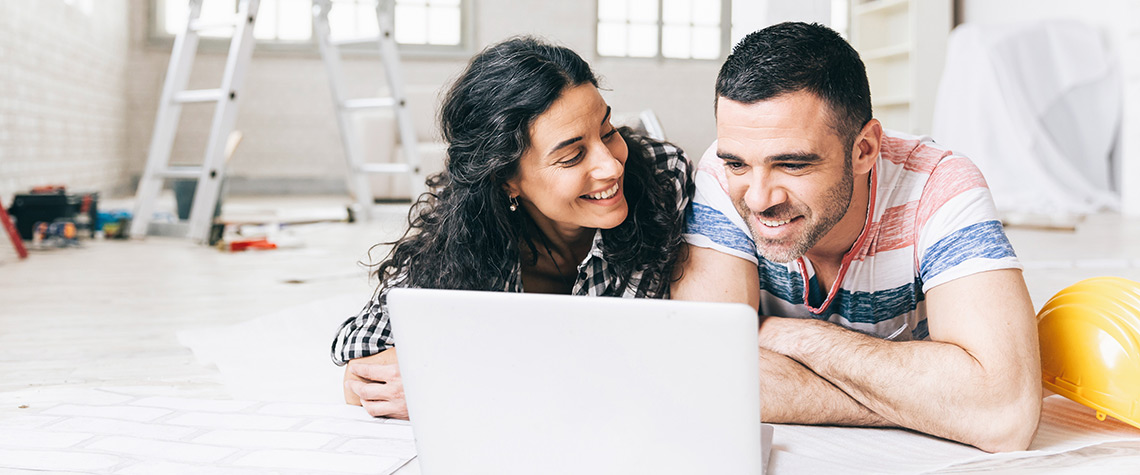 Man and woman using a laptop in a room that is being renovated