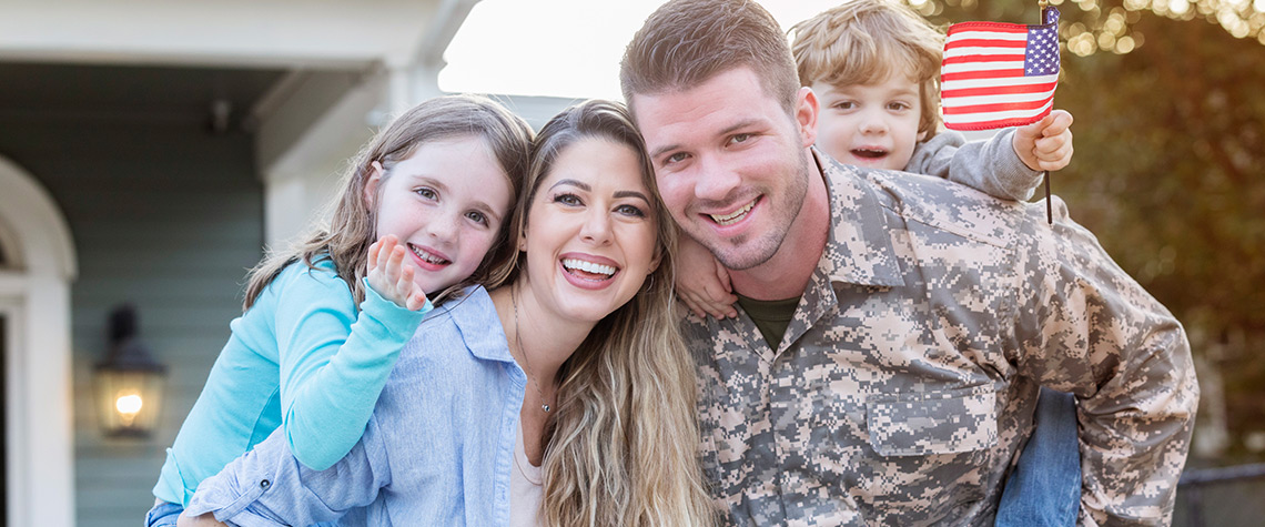 A military veteran with his family in front of a home