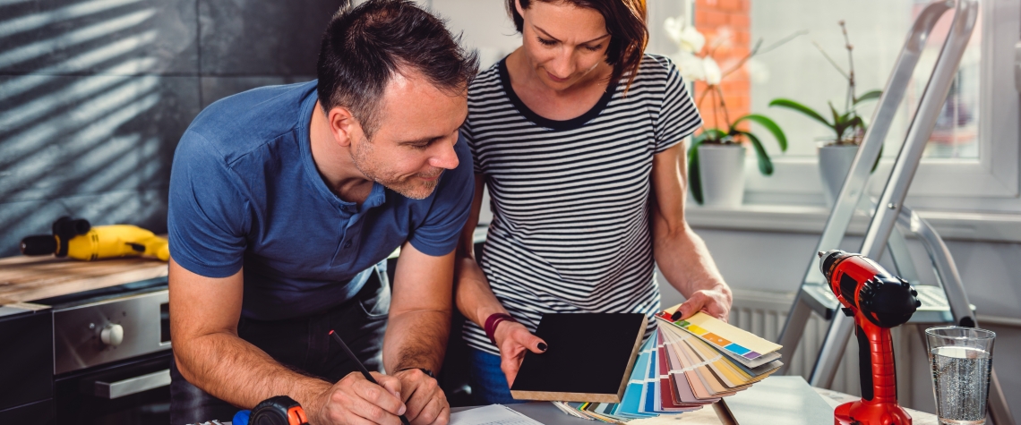 Couple standing by the table and looking at color swatch during kitchen renovation