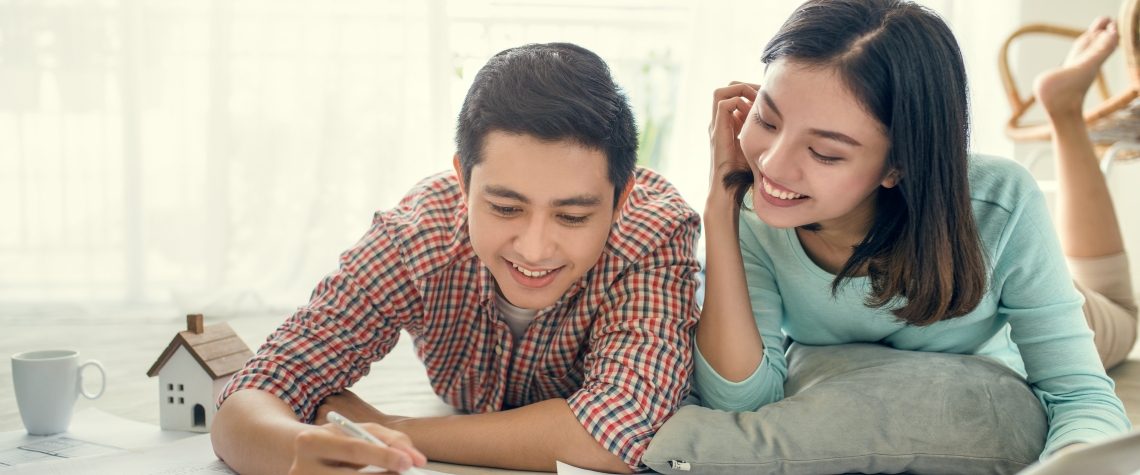 Close up of happy asian couple looking at blueprint at home