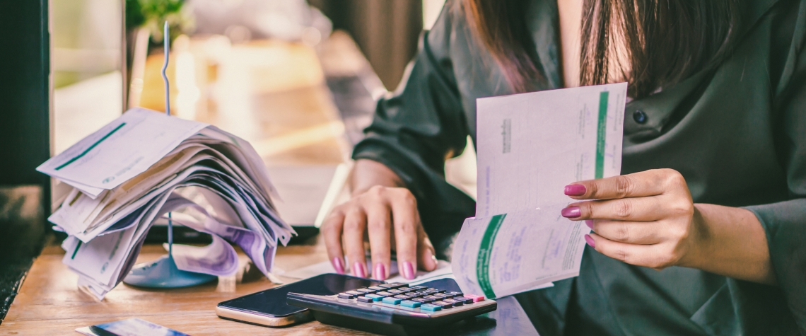 Asian woman hand holding financial bills calculating debt from credit cards on desk