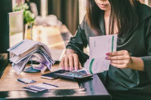 Asian woman hand holding financial bills calculating debt from credit cards on desk