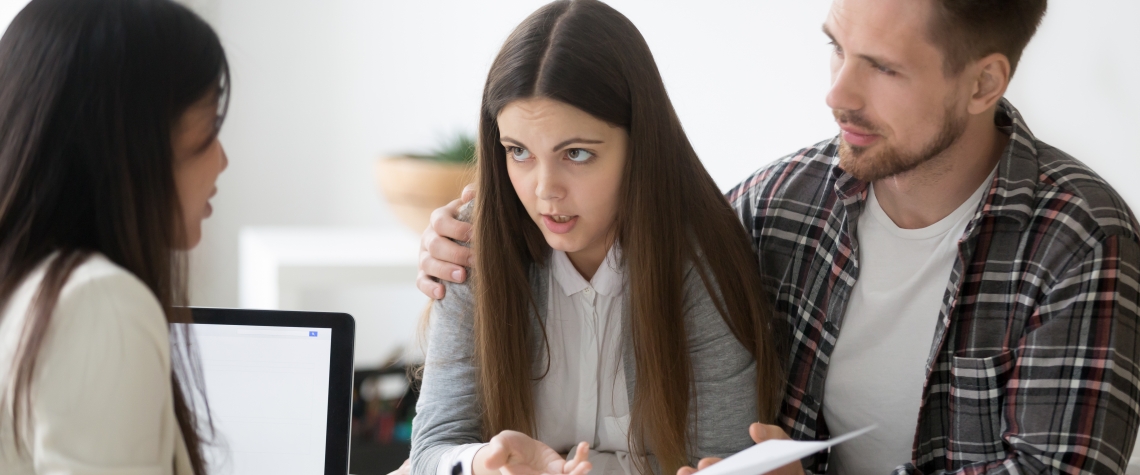 Young spouses having dispute with real estate agent, dissatisfied with ownership contract conditions, couple disagreeing on mortgage loan, expressing claims and discussing problems with realtor