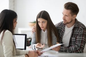 Young spouses having dispute with real estate agent, dissatisfied with ownership contract conditions, couple disagreeing on mortgage loan, expressing claims and discussing problems with realtor