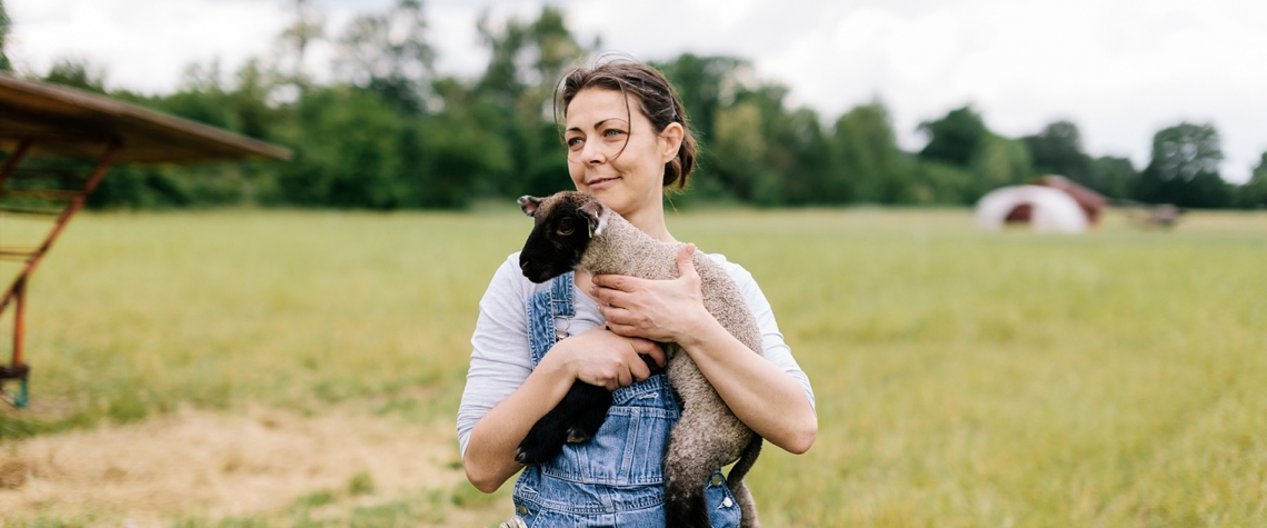 Owner of a farm holding a lamb