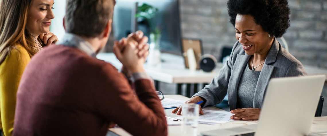 Cheerful African American financial advisor on a meeting with a couple. Happy African American having consultations with a couple during the meeting.
