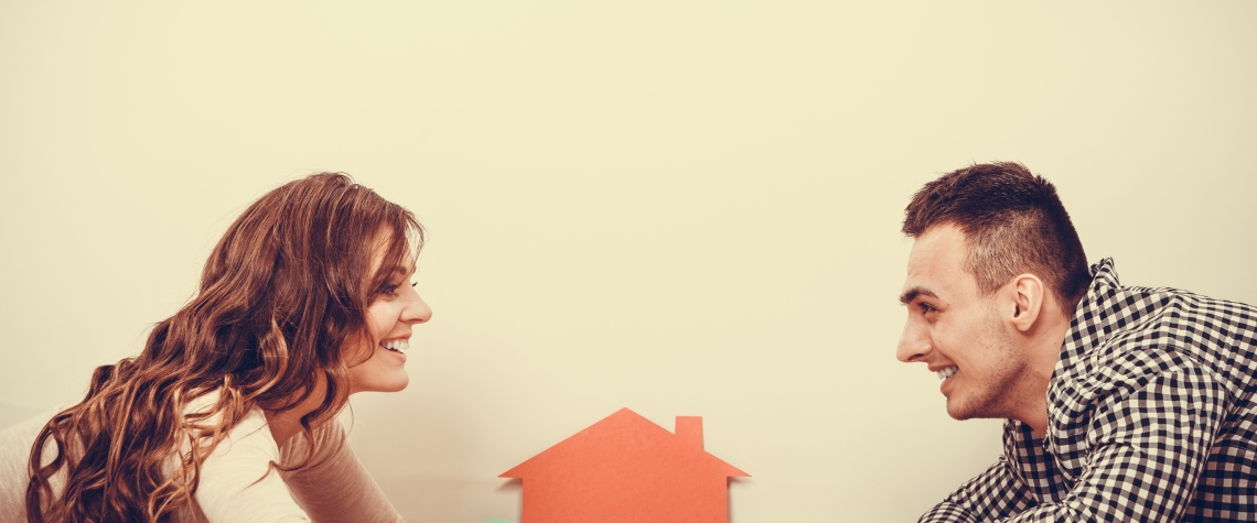 real estate, family and couple concept - smiling couple lying on floor with symbol house and key daydreaming at home, vintage filter