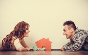 real estate, family and couple concept - smiling couple lying on floor with symbol house and key daydreaming at home, vintage filter