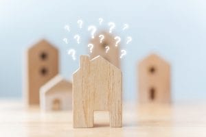 Selective focus wooden houses with question mark on table