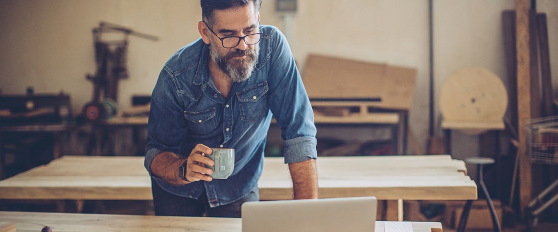 Man with coffee looking at laptop