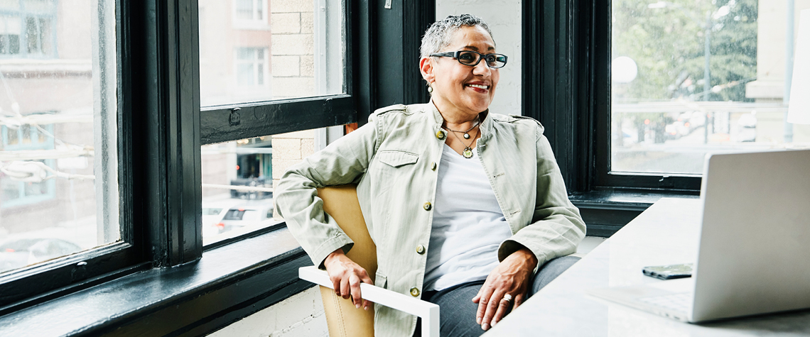 Woman sitting at a desk smiling at her computer