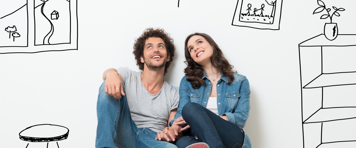 Portrait Of Happy Young Couple Sitting On Floor Looking Up While Dreaming Their New Home And Furnishing