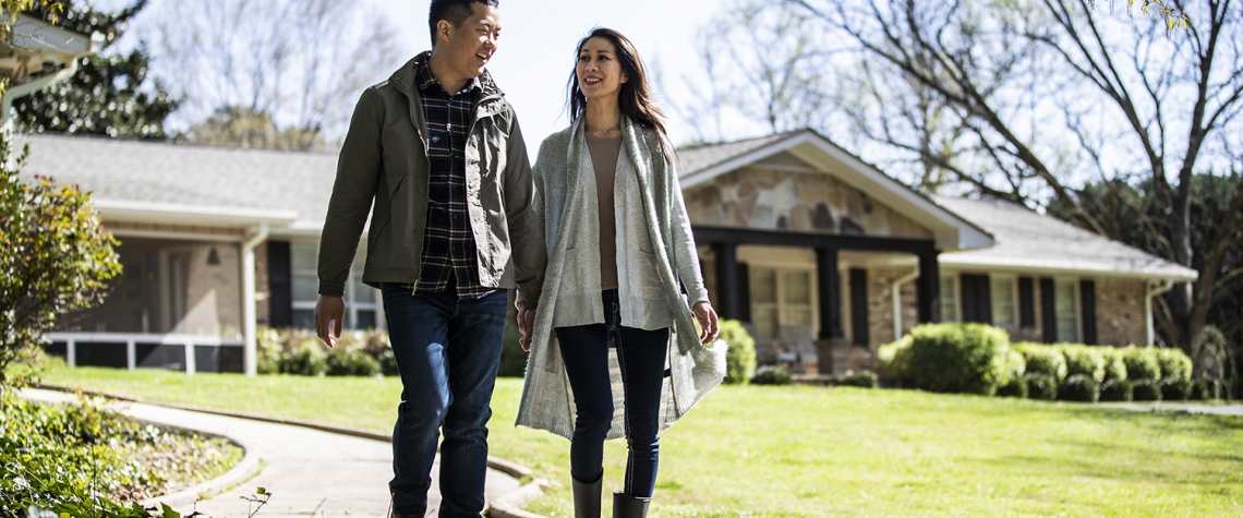 Married couple walking on pathway in front of home