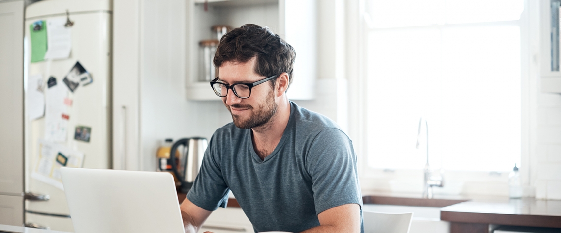 Shot of a young man using a laptop while having breakfast in the kitchen at home