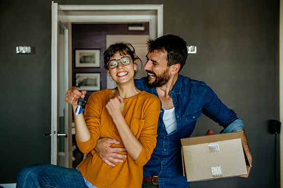Happy couple with moving box and housekeys