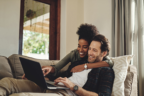 Couple sitting on the couch looking at a compuer