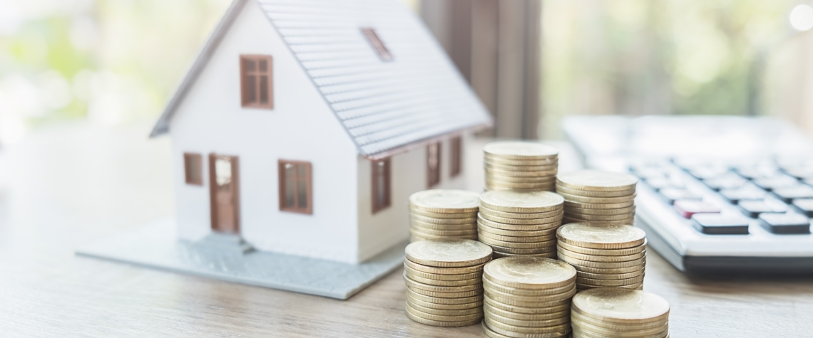 Small model home with coins next to it