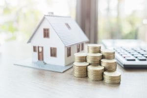 Small model home with coins next to it