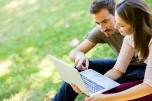 couple looking at computer in the grass