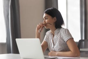 Thoughtful anxious asian business woman looking away thinking solving problem at work, worried serious young chinese woman concerned make difficult decision lost in thought reflecting sit with laptop